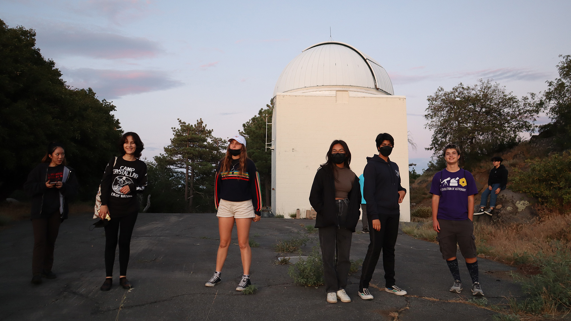 Students stand in front of observatory tower at dusk